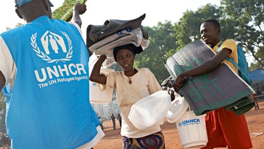 En kvinnor och hennes son får förnödenheter som plastmattor, dunkar, presenningar, hink och myggnät från UNHCR i Bossangoa.