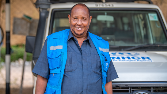 UNHCR:s chaufför Ahmed Abdinoor står framför en UNHCR-bil.