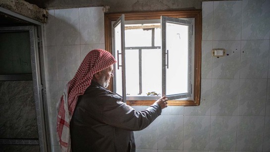 En man tittar ut genom sitt nya fönster i Syrien.